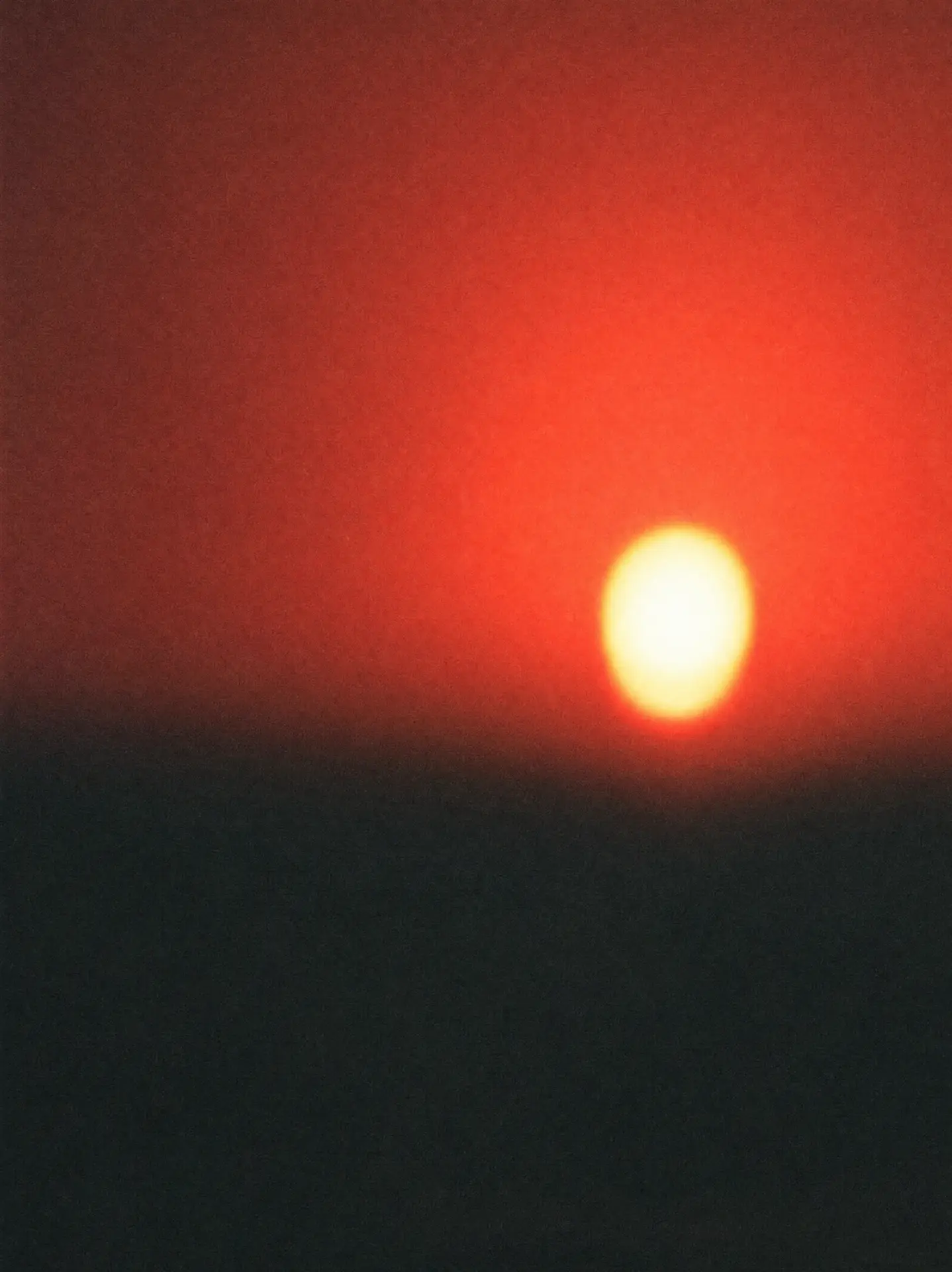 Blurred red sun low over a dark horizon