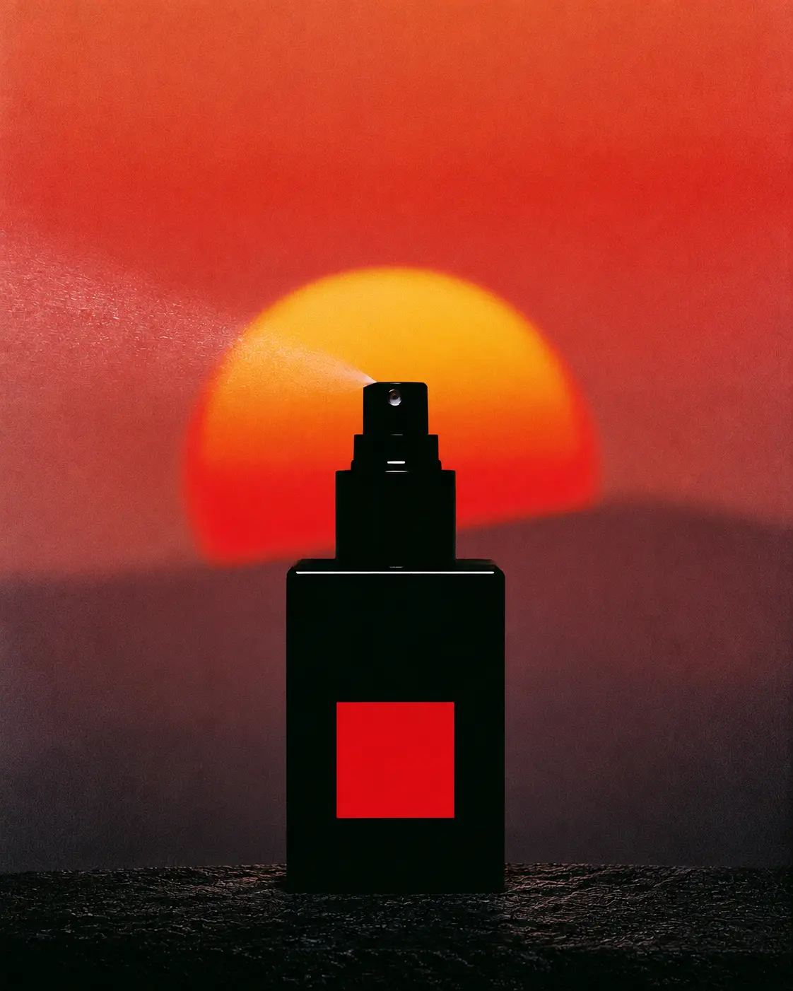 Black fragrance bottle spraying against a large setting sun